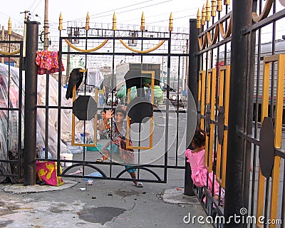 Little brown street girl looks out through the bars of the fence Editorial Stock Photo