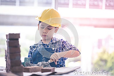 Little Builder boy learning how to build brick wall in vintage tone Stock Photo