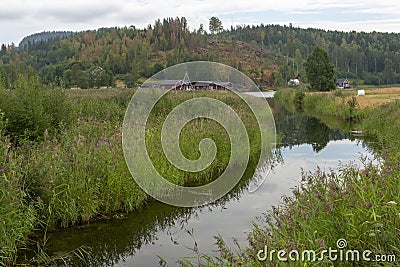Little calm river with reflections in the vater and hill with forest in background Stock Photo