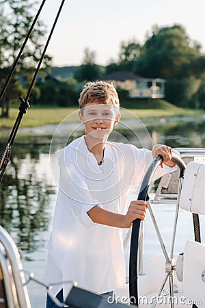 a little captain at the helm on a yacht. a little boy at the helm of the captain on a yacht at sunset Stock Photo