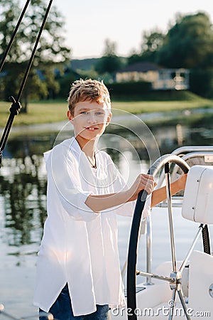 a little captain at the helm on a yacht. a little boy at the helm of the captain on a yacht at sunset Stock Photo