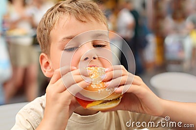 Little caucasian boy eating burger Stock Photo