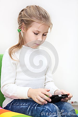 Little Caucasian girl has unlimited net access. Internet usage with smartphone Stock Photo