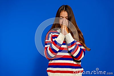 Little caucasian girl isolated on blue background holding hands in pray near mouth, feels confident Stock Photo
