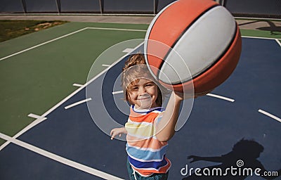 Little caucasian sports kid playing basketball holding ball with funy face. Stock Photo