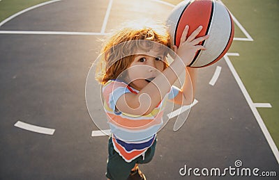 Little caucasian sports kid playing basketball holding ball with funy face. Stock Photo