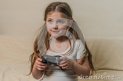 Little charming girl child plays a joystick in a video game on a game console Stock Photo