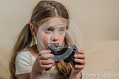 Little charming girl child plays a joystick in a video game on a game console Stock Photo