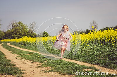Little charming girl in summer dress running in rural path in green nature Stock Photo