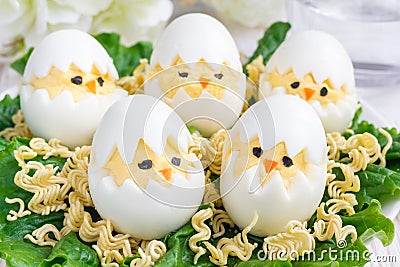 Little chicken in nest, deviled eggs served with salad and dry ramen on plate, horizontal Stock Photo