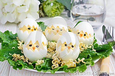 Little chicken in the nest, deviled eggs served with salad and dry ramen on white plate, horizontal Stock Photo