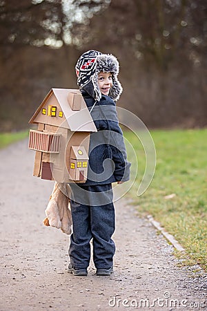 Little child, blond boy with pet dog, carying home on his back, kid, having paper house Stock Photo