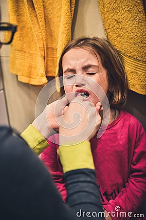 Little child is crying while mother brushes her teeth. Stock Photo