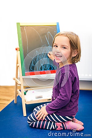 Little child is drawing with color chalk on the chalk board Stock Photo