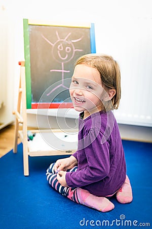 Little child is drawing with color chalk on the chalk board Stock Photo