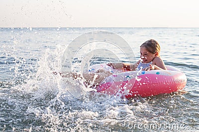 Little child girl laughing and crying in the splash of waves at sea on a sunny day Stock Photo