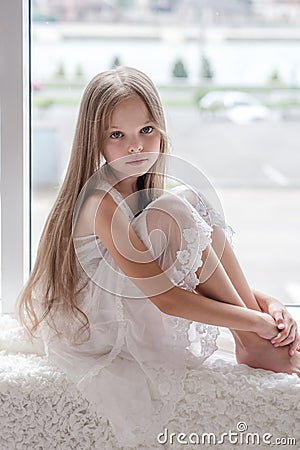 Little girl sits alone front of the window Stock Photo