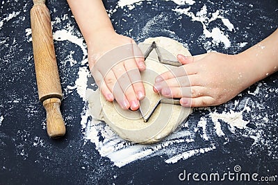 Little child hands with cookie cutter like a star making handmade traditional Christmas cookies. An overhead photo of kid`s hands, Stock Photo