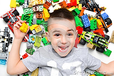 Little child playing with lots of colorful plastic toys indoor Stock Photo