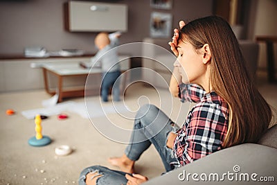 Little child playing in room, mother in stress Stock Photo