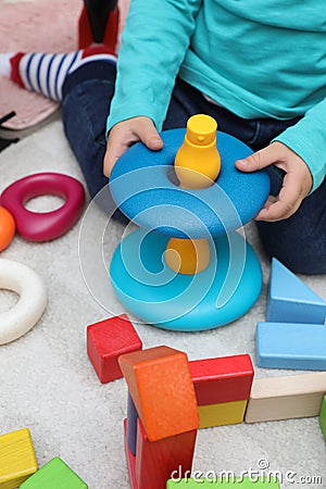 Little child playing with stacking toy on carpet, closeup Stock Photo
