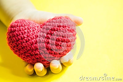 Child`s hand with a red heart on yellow background Stock Photo