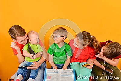 A little child sits with his elder brother in his arms, and the children look at her. Children read stories with a book, and the Stock Photo