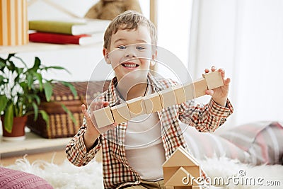 Little child sitting on the floor. Pretty boy palying with wooden cubes at home Stock Photo