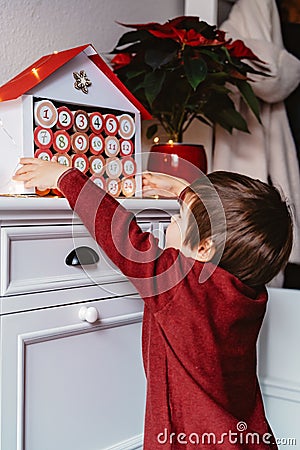 Little child taking handmade advent calendar made from toilet paper rolls. Stock Photo