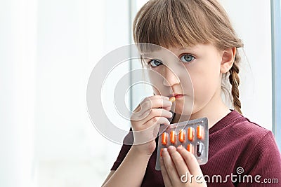 Little child taking pill indoors. Danger of medicament intoxication Stock Photo