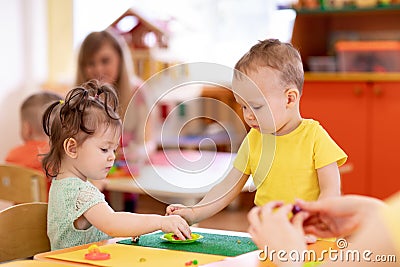 Little kids girl and boy molding from play dough in creche Stock Photo