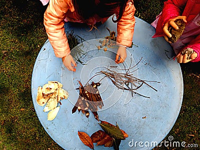 Little children playing, expolring and gardening in the garden with soil, leaves, nuts, sticks, plants, seeds during a school Stock Photo