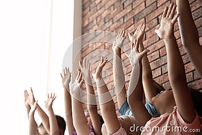 Little children raising hands together indoors Stock Photo