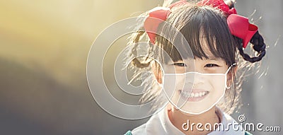 Little chinese girl wearing face mask happy at school. Covid-19 coronavirus Stock Photo