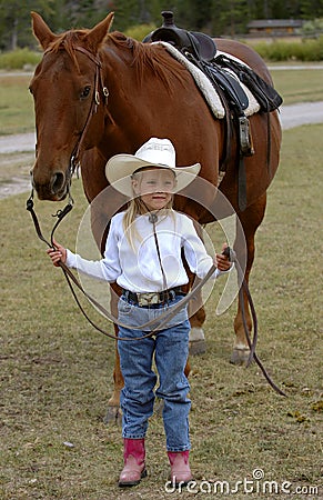 Little Cowgirl Holding Chestnut/Sorrel Horse Stock Photo