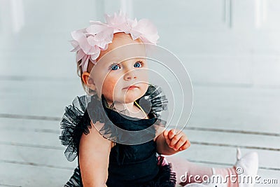 Little crawling baby girl one year old siting on floor in bright light living room smiling and laughing Stock Photo