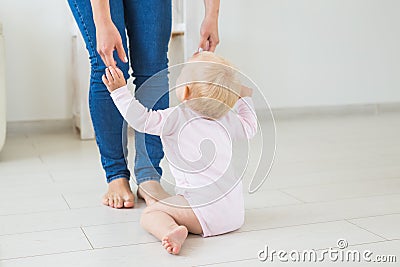 Little crawling baby girl one year old sitting on floor in bright light living room smiling and laughing. Happy toddler Stock Photo