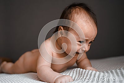 Little crying baby daughter on bed. One month age. Newborn cute happy beautiful girl smiling. Breast-feeding. Happiness Stock Photo