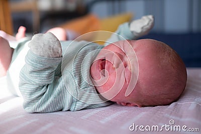Little crying caucasian newborn baby on her bed suffering from colic Stock Photo