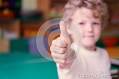 Little curly boy show his thumb up. Image with depth of field. Stock Photo