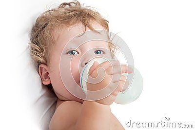 Little curly-headed baby sucks a bottle of milk Stock Photo