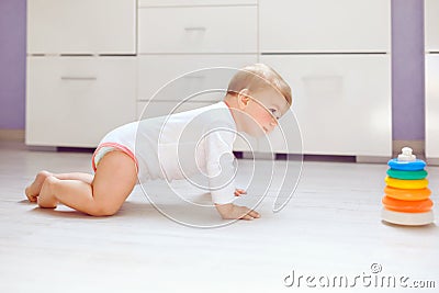 Little cute baby girl learning to crawl. Healthy child crawling in kids room. Smiling happy healthy toddler girl. Cute Stock Photo