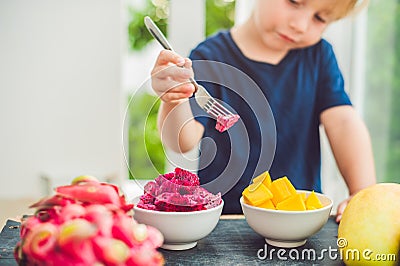 Little cute boy eating mango on the terrace Stock Photo