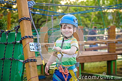Little cute boy enjoying activity in a climbing adventure park on a summer sunny day. toddler climbing in a rope playground Stock Photo