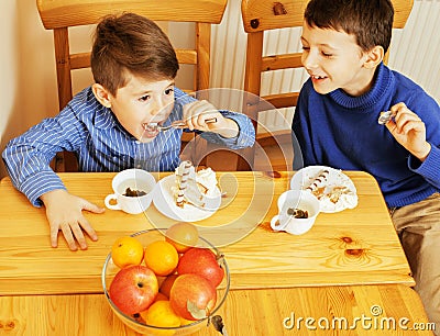 Little cute boys eating dessert on wooden kitchen. home interior Stock Photo