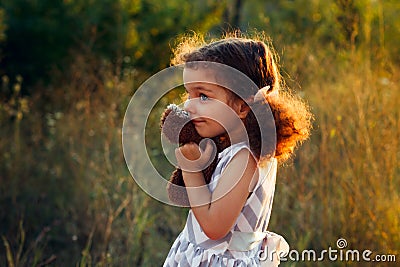 Little cute curly girl hugd a fluffy toy owl. Toddler girl play with sweet doll. A beautiful sunlight, warm colours. Autumn time Stock Photo