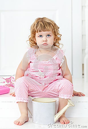 Little cute curly girl in a pink dress with polka dots sitting on the white porch Provence style Stock Photo