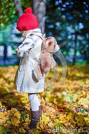 Little cute girl with a backpack-bear walks in the Stock Photo