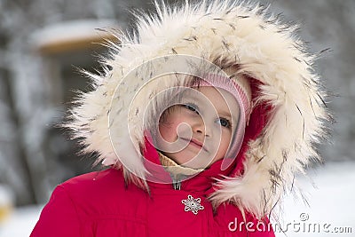 Little cute girl in a big fur hood thinks about something good Stock Photo