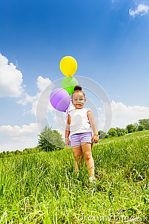 Little cute girl holding three flying balloons Stock Photo